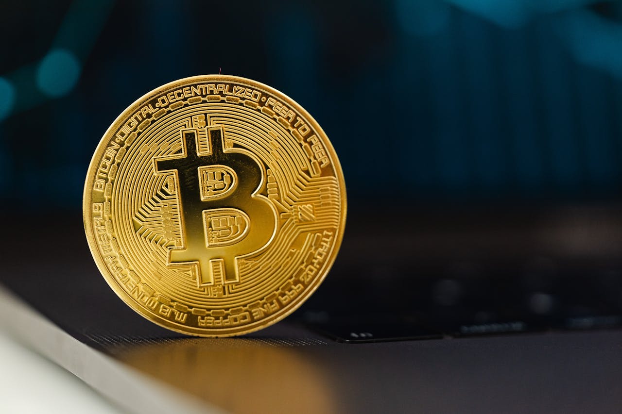 Home Golden Bitcoin coin standing upright on a laptop keyboard, representing digital currency.